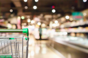 Empty green shopping cart with abstract supermarket grocery store blurred defocused background with bokeh light